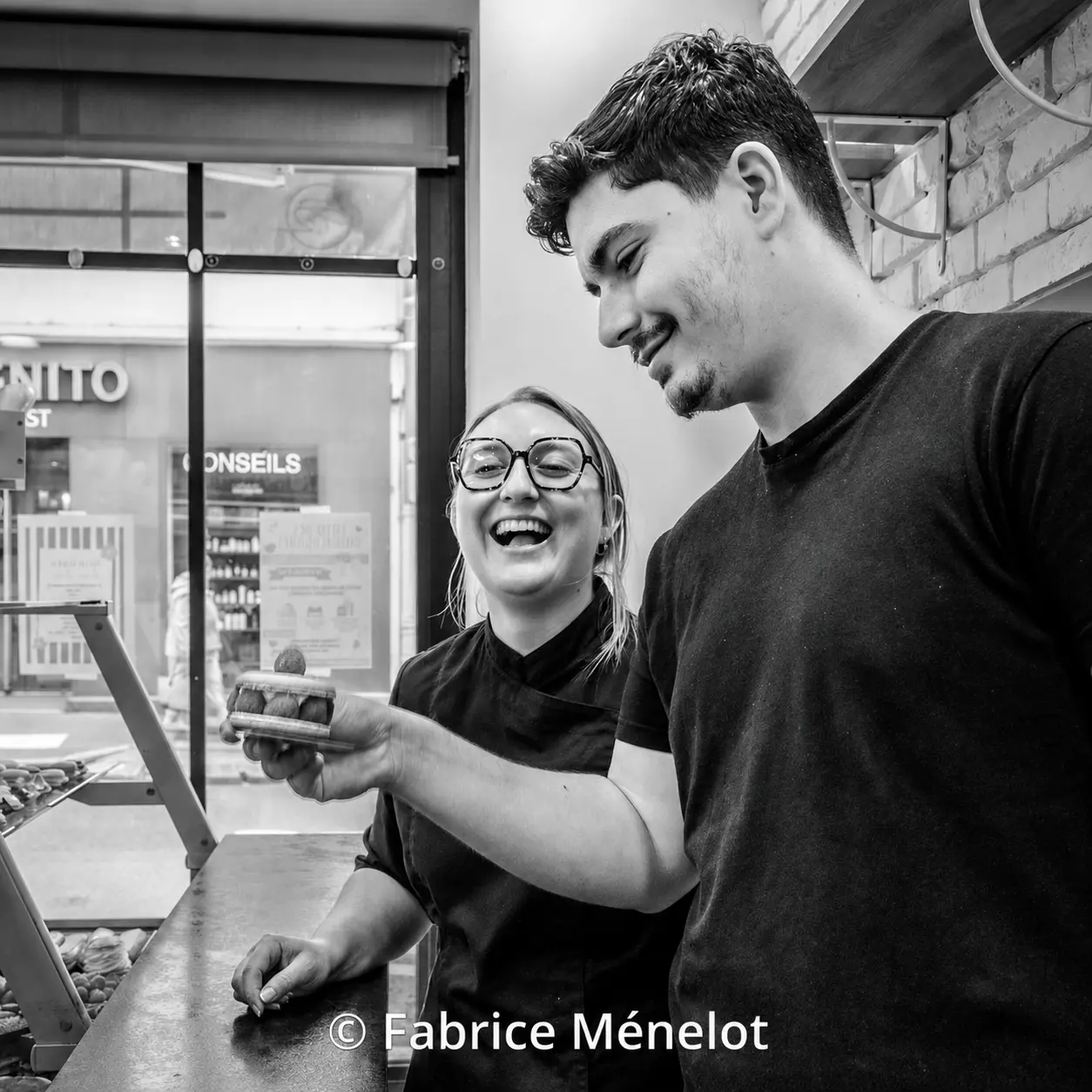 Estelle et Roberto souriant ensemble derrière le comptoir de leur boulangerie